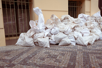 Big white reusable recycling package, filled bags on the city street,  piled up in a big pile on a paving stones.