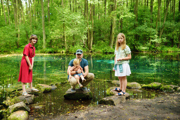 Fototapeta premium Family of four exploring Niebieskie Zrodla or Blue Springs, famous for two pools fed by an underground spring.