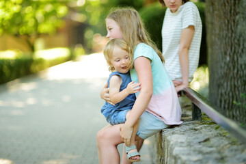 Cute big sister cuddling with her toddler brother. Adorable teenage girl holding baby boy. Children with large age gap.