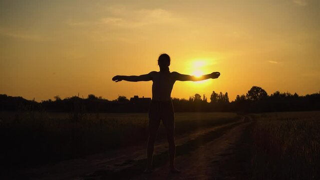 Sports and recreation. Silhouette of a teenager boy who runs at sunset. The guy trains in nature in the setting sun. The concept of sport, health, freedom.