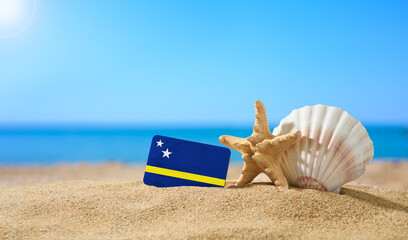 Fototapeta na wymiar Tropical beach with seashells and Curacao flag. The concept of a paradise vacation on the beaches of Curacao.