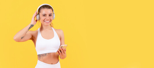 happy sport woman with headphones and smartphone on yellow background. Woman isolated face portrait, banner with mock up copyspace.