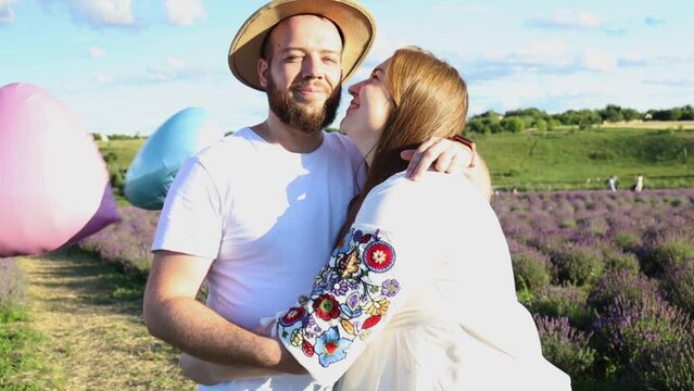 Happy couple holding surprise balloon during gender reveal party in lavender field. 