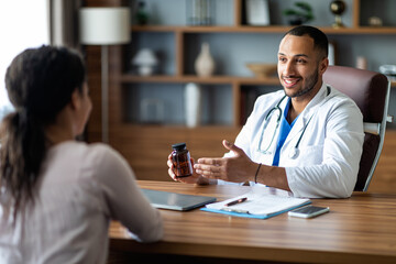 Handsome arab doctor holding jar with drugs
