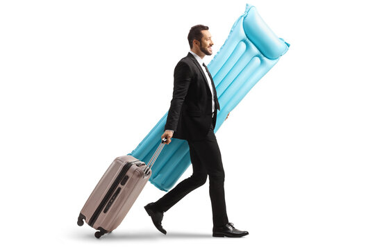 Full Length Profile Shot Of A Businessman Carrying A Water Floating Mattress And Pullung A Suitcase