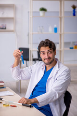Naklejka na ściany i meble Young male chemist working at the lab