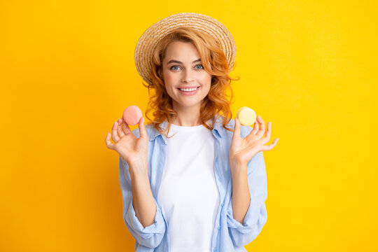 Cute young woman hold macaroon. Diet, dieting concept. Beautiful smiling young girl eating colorful macaroons over yellow background.