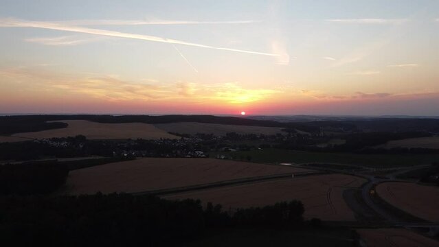 Drohnenmaterial beim Sonnenuntergang &uuml;ber einem Dorf und kleinen Wald
