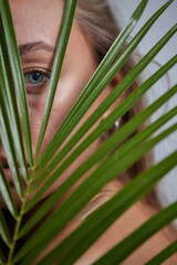 Alluring in good shape bewitching female model over 20s in sandy clothes cuddling the fern leave...