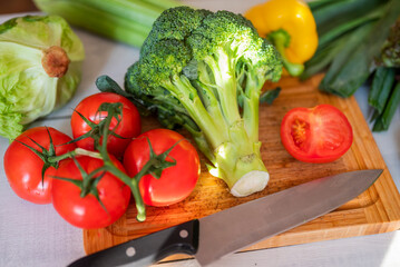 fresh vegetables for iceberg salad with paprika with cabbage broccoli tomatoes and celery on a wooden board