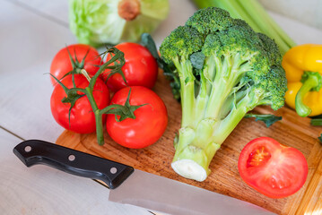 fresh vegetables for iceberg salad with paprika with cabbage broccoli tomatoes and celery on a wooden board