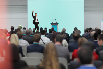 Businessman waving on stage and people watching in the audience