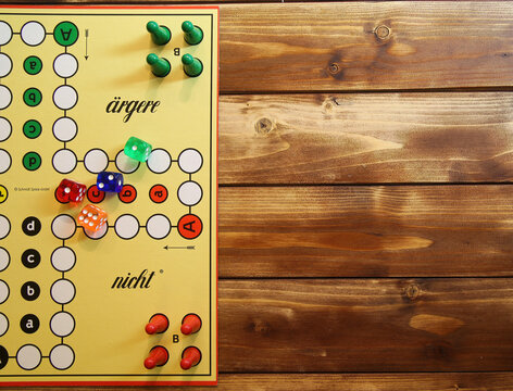 Viersen, Germany - May 9. 2021: Top down view on yellow strategy game board with colorful pieces and dices of mensch &auml;rgere dich nicht, wooden background