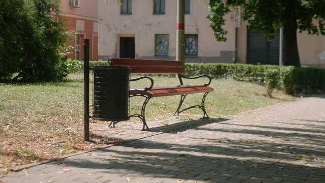 Ławka w parku w obszarze podmiejskim, lekko zacieniona w samo południe