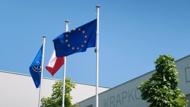 Powiewające na wietrze flagi unii europejskiej, Polski oraz powiatu krapkowickiego w wojew&oacute;dztwie Opolskim