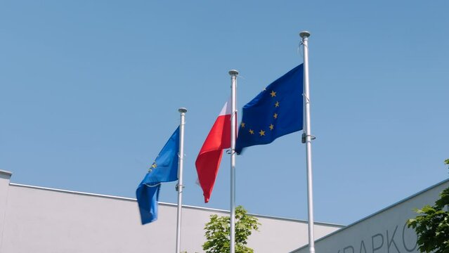Powiewające na wietrze flagi unii europejskiej, Polski oraz powiatu krapkowickiego w wojew&oacute;dztwie Opolskim