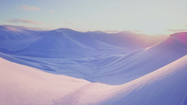 Drone flight near Longyearbyen The sun setting behind the snowy mountains on Svalbard. White snowy mountains