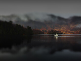 Bateau avec effet miniature se baladant au milieu d'un lac &eacute;cossais dans un paysage brumeux. 