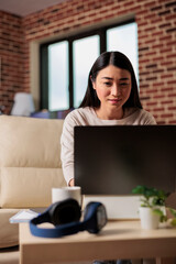 Natural young asian woman pleased happy cheerful cute beautiful freelance sit indoors in home office using laptop computer working web technology online web 3.0 application