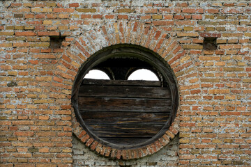 An old brick non-residential building. An ancient historical building. A large round window in an old brick building.