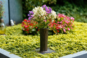 Fototapeta na wymiar metal vase with fresh flower decoration on a grave