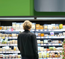 Young man shopping in supermarket, reading product information