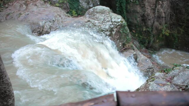 A waterfall at San Fele, Italy, inside a forest, going down with a strong water current. Rainy day, panning shot.
