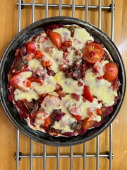 Close up of home made freshly baked hot vegetarian pizza lunch with sour dough bread base, mushroom, tomato, onion, pepper, courgette, cheese topping with basil herbs on wood kitchen surface flat lay