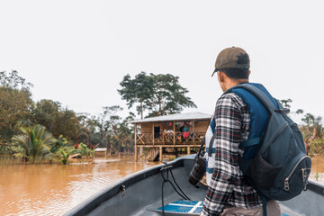 Latino man sailing a boat down a muddy river and visiting an indigenous community in El Rama,...