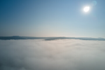 Aerial view from high altitude of earth covered with white puffy cumulus clouds on sunny day