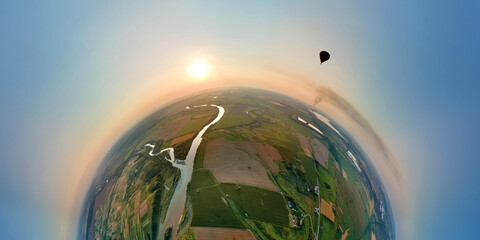 Aerial view from high altitude of little planet earth with small hot air baloon flying on orbit...