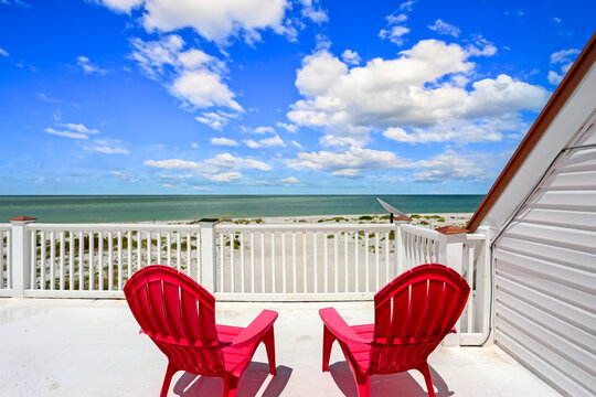 View of the Beach on a Balcony with Two Chairs and a Blue Sky and Fluffy Clouds in North Captiva Island, Florida