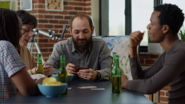 Competitive people playing board games with cards at table, enjoying tactics with leisure activity. Positive group of friends having fun together with strategy card competition. Close up.