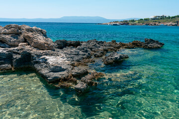 Amazing shot of a sea coast with clear blue water and stones in the foreground. © Vahid