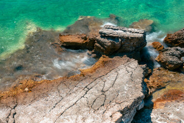 Amazing shot of a sea coast with clear blue water and stones in the foreground.