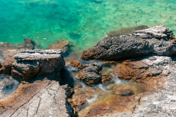 Amazing shot of a sea coast with clear blue water and stones in the foreground.