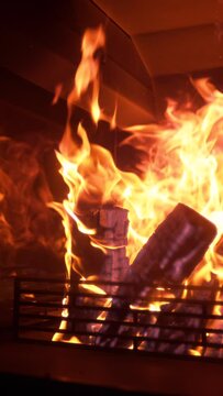 SLOW MOTION, CLOSE UP: Idyllic shot of large logs burning inside a vintage fire place. Close up of a large fire burning in the middle of a dark living room in a luxurious home on a cold winter night