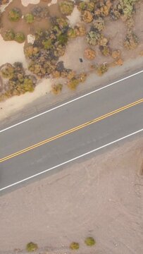 TOP DOWN: Flying above Route 66 as the lone tourist car drives along the famous straight highway. Drone point of view of the scenic highway crossing the rugged landscape of rural California, USA.