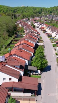 AERIAL: Terraced houses sprawl across the vast green expanse in Slovenia. Scenic aerial view of an idyllic suburban neighborhood near Ljubljana. Flying above a quiet suburbia on a sunny summer day.