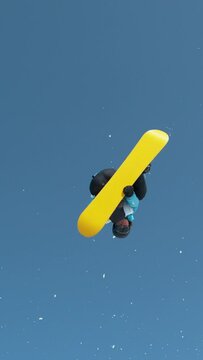 SLOW MOTION TIME WARP: Spectacular shot of a young male snowboarder jumping off a kicker and doing a spinning trick. Athletic male tourist snowboarding in Alps jumps into air and performs a spin trick