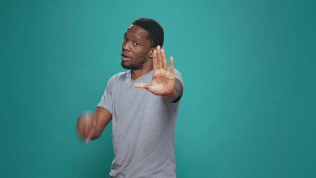 Portrait of person doing talk to the hand rejection gesture, expressing refusal and disapproval. Negative man advertising no sign and disagreeing, showing dislike symbol in studio.