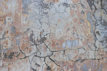 Vintage wall texture. Rough surface of the plastered concrete wall of the building. A pattern with many cracks and old faded peeling paint. Perfect for background and design. Closeup.