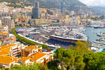 Luxury yachts line the harbor during Grand Prix Race day at Monte Carlo, Monaco, with the mountains, city and casino in view along the coast.