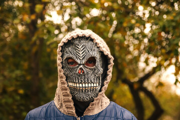 Defocus Halloween people portrait. Person in grim reaper mask standing on nature autumn background....