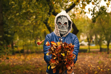 Defocus Halloween people portrait. Person in grim reaper mask standing on nature autumn background...