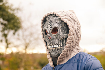 Defocus Halloween people portrait. Person in grim reaper mask standing on nature autumn background....