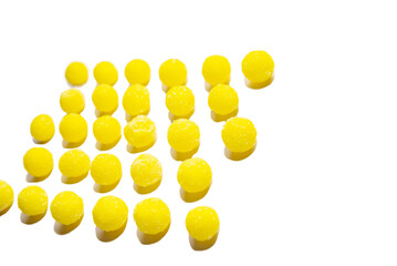 a lot of yellow round candies are laid out in a pattern on a white background. close-up, perspective