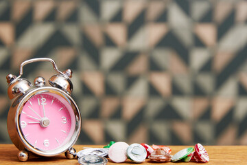 Small fancy alarm clock and colorful buttons on the wooden bed table. Teenage girl accessories background with copy space