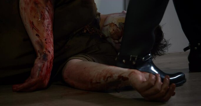 Thinking zombie set a trap for his victim by closing eyes and lying on floor pretending to be dead. Person in boots steps over an undead man without suspecting anything
