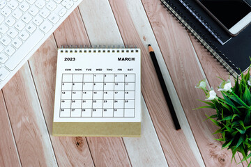 White March 2023 desk calendar on wooden desk. Directly above. Flat lay.